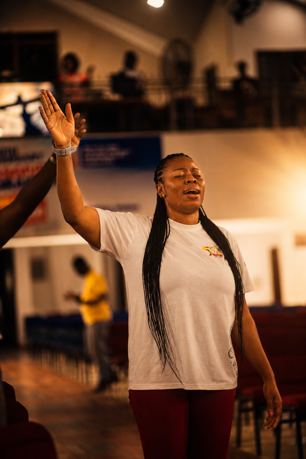A woman worshipping with her hand raised and eyes closed